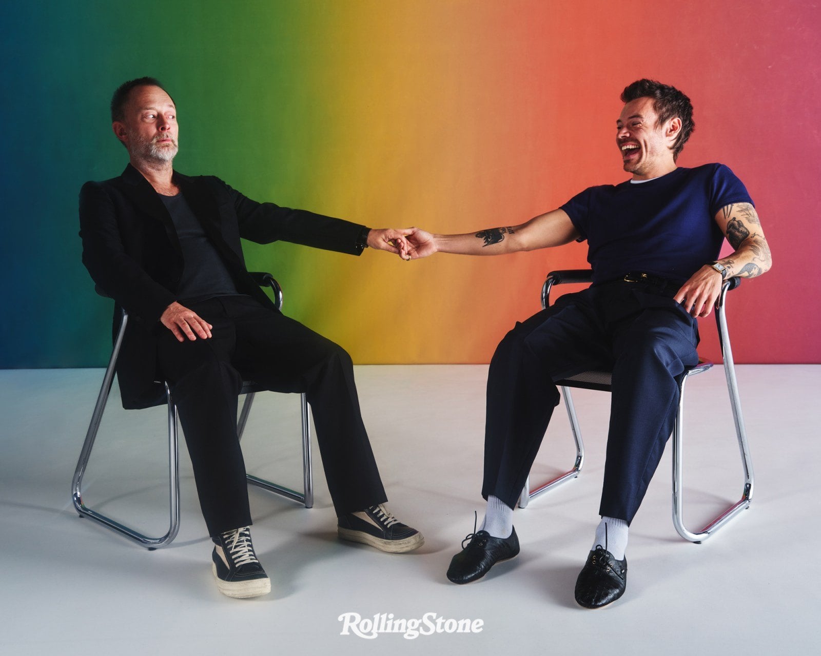 Thom Yorke y Harry Styles sentados frente a un fondo de colores durante la sesión de Rolling Stone en Londres